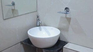 Casa de banho com lavatório branco, espelho e torneira.