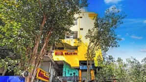 Um edifício de vários andares com fachada amarela, um letreiro com 'Hotel Relax Inn' e uma entrada visível.