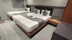 Quarto de hotel com duas camas de solteiro, cabeceira de madeira, mesa de cabeceira com bandeja e uma janela grande.