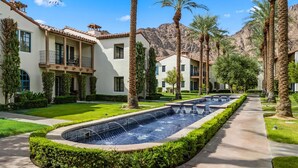 A residential area with a swimming pool, palm trees, and houses with balconies. - LV033 Quaint Downstairs Legacy Villas Suite (La Quinta)