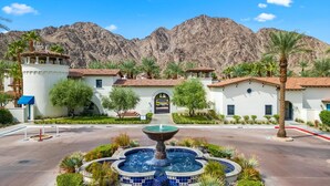 A courtyard with a fountain, palm trees, and a view of mountains. - LV033 Quaint Downstairs Legacy Villas Suite (La Quinta)