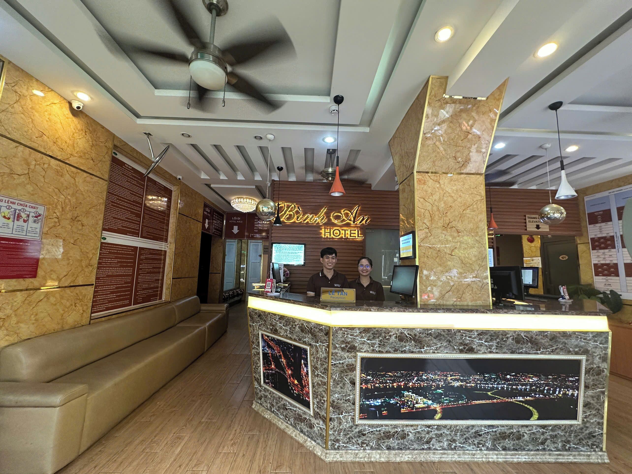 A hotel reception area with a marble counter, a reception desk, and a large illuminated sign above.