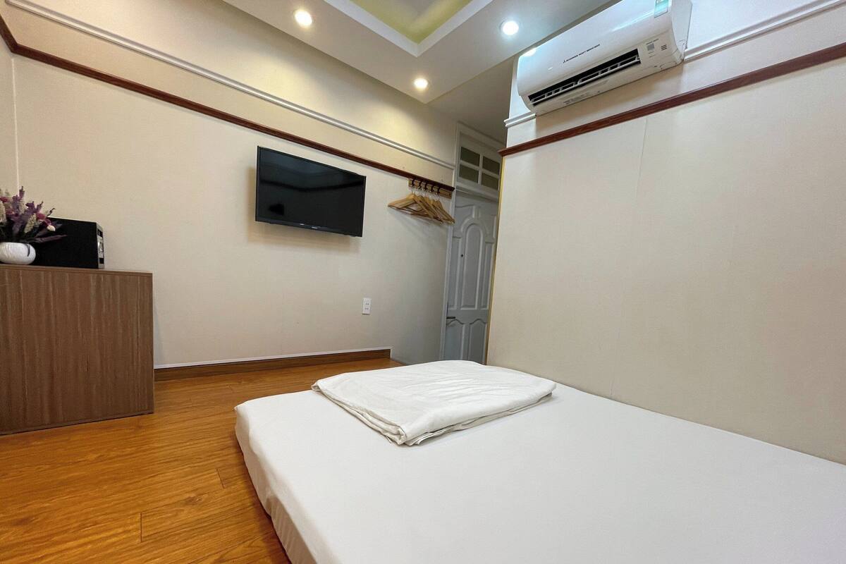 Una camera d'albergo con un letto, una TV a parete e un condizionatore d'aria.