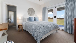 Una camera da letto con un letto, un comodino, una lampada, un elemento decorativo a parete e vista panoramica attraverso una porta vetrata.