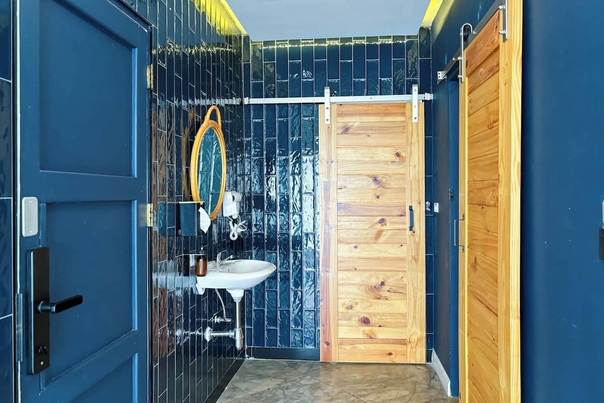 A bathroom with a wooden door, a sink, and a mirror.