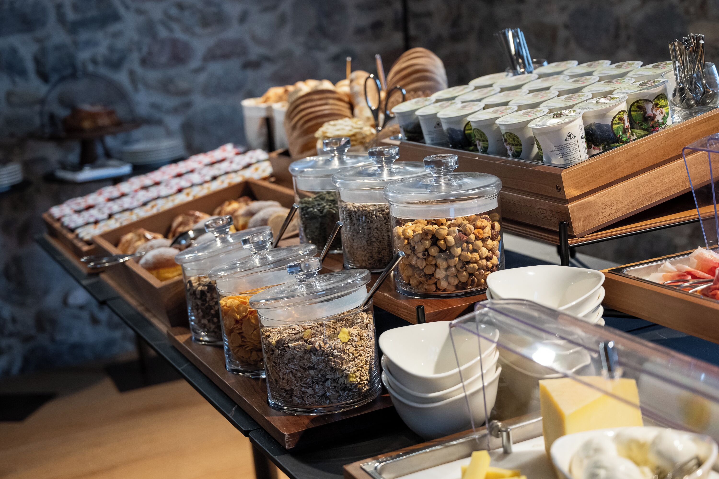 A buffet with various food items and containers, including jars of nuts and seeds, and a selection of pastries.
