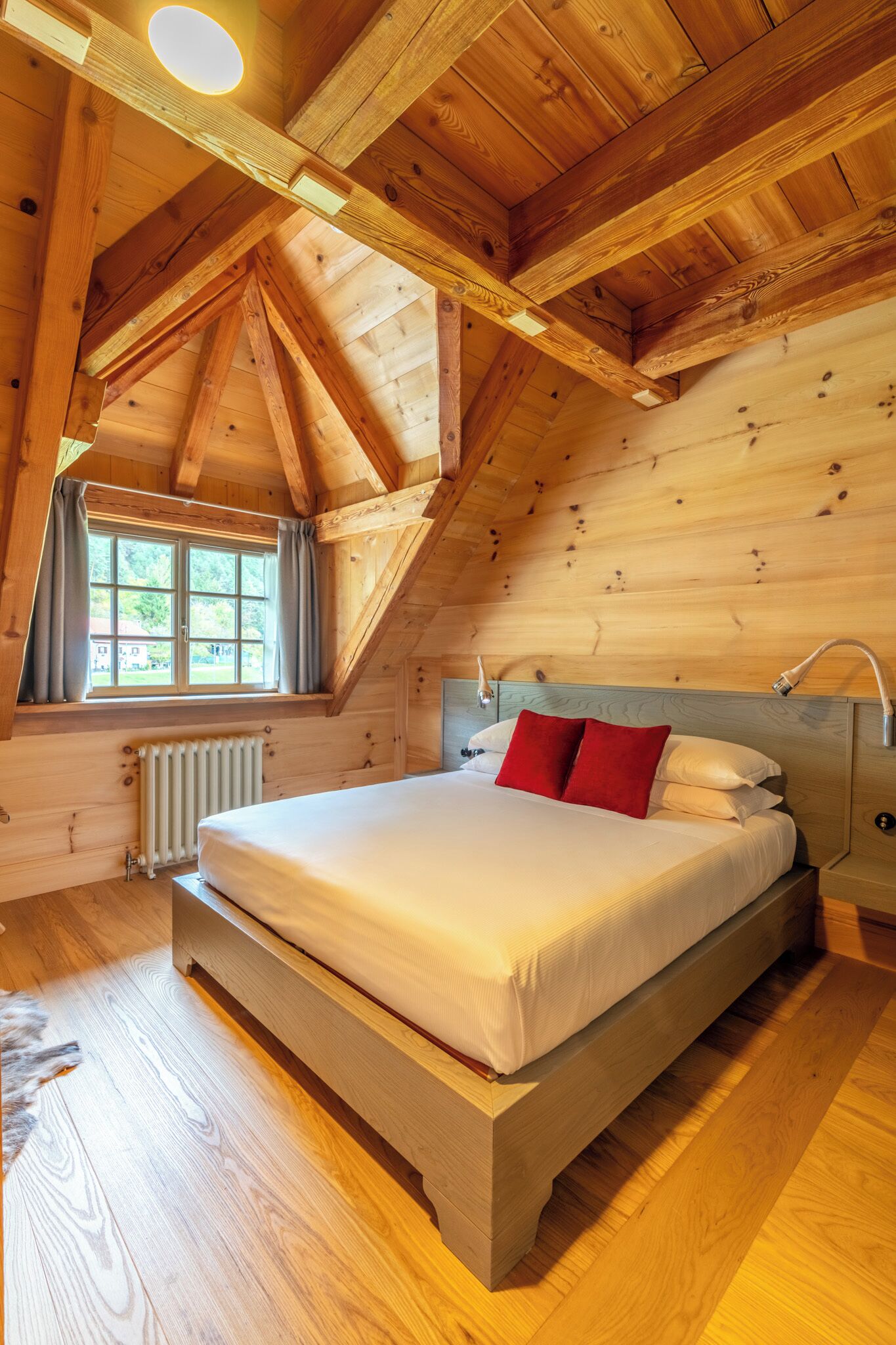 Une chambre dans une cabane en bois, avec un lit, une fenêtre et un radiateur.