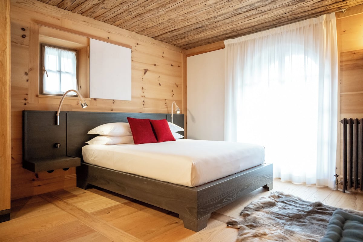 Une chambre à coucher aux murs lambrissés, avec un lit, des tables de chevet et une fenêtre avec des rideaux.