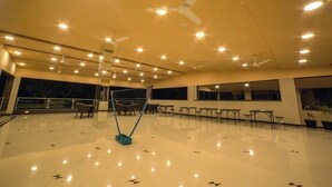 A spacious indoor area with multiple ceiling fans, tables, and chairs arranged for gatherings. - Amansaraa Bhide Retreat (Alibag)