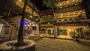 A multi-story building with a courtyard, outdoor seating area, and a tree in the center. - Amansaraa Bhide Retreat (Alibag)