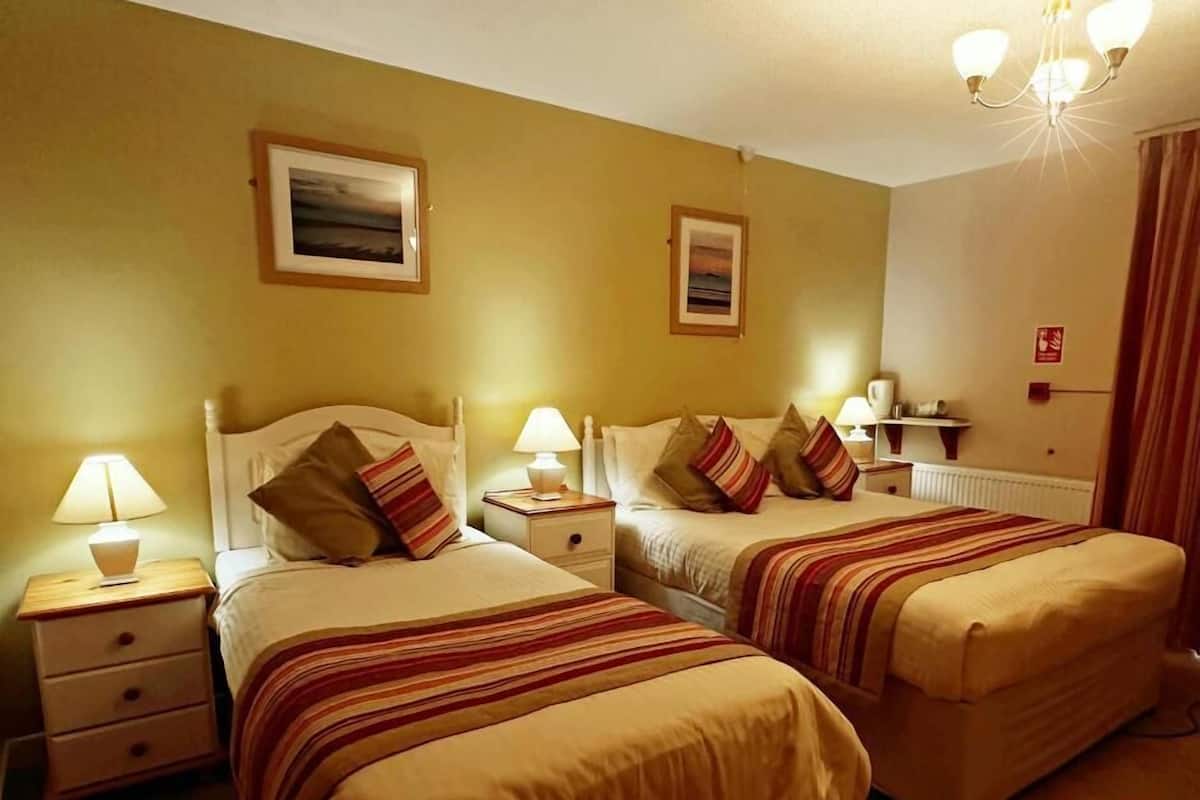 Une chambre d’hôtel avec deux lits, chacun doté d’une table de chevet et d’une lampe, et une grande fenêtre offrant une vue dégagée.