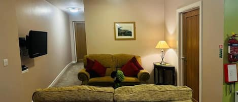 A hallway with a sofa and a television, a lamp, and a framed picture on the wall.