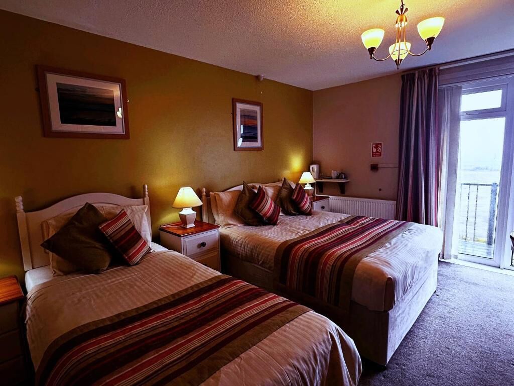 Una habitación de hotel con dos camas, una ventana con vistas y un candelabro.