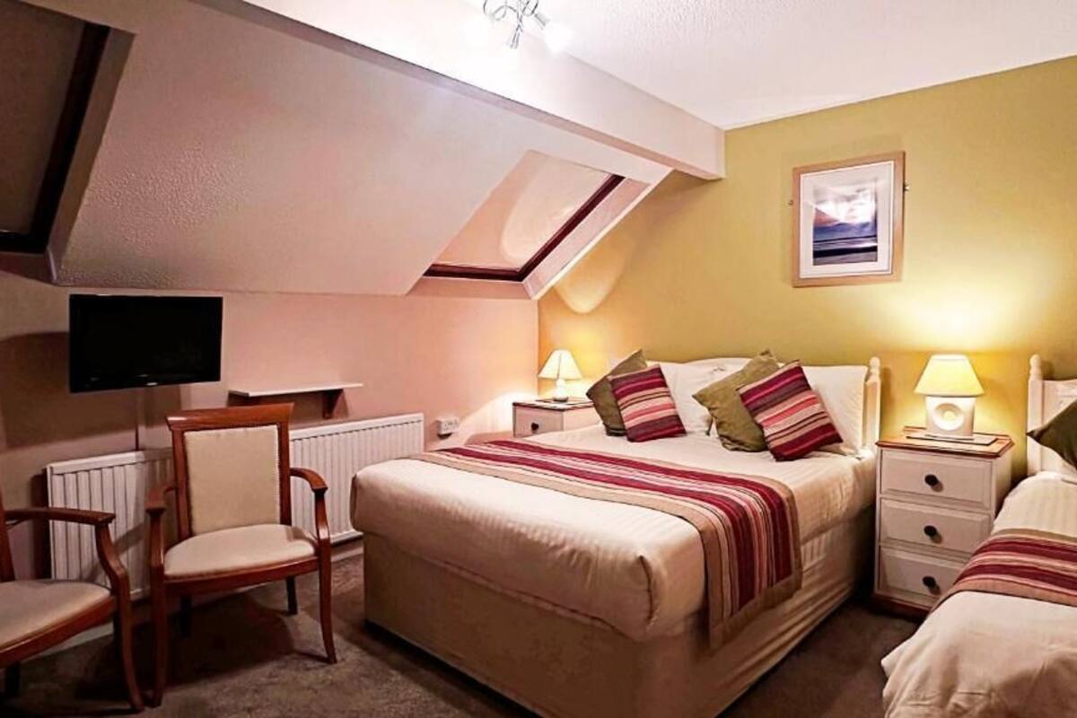 Une chambre avec deux lits, une télévision, une chaise et une table de chevet avec des lampes.