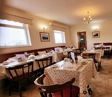Un comedor con varias mesas y sillas, cada conjunto con manteles y cubiertos.