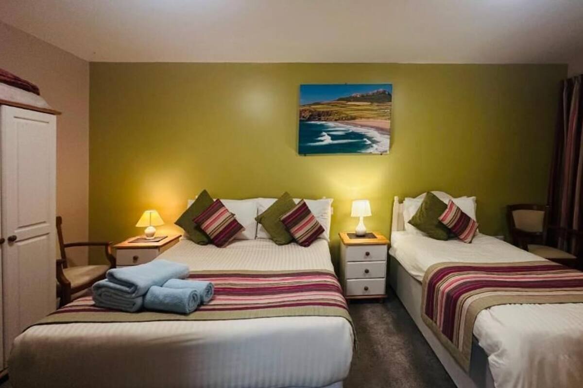 Une chambre d’hôtel avec deux lits, un tableau représentant un paysage côtier et une vue sur la mer.