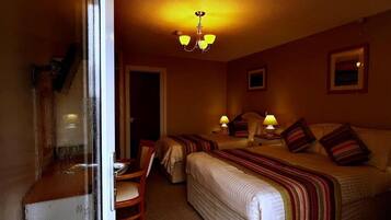 A hotel room with two beds, a dining area, and a chandelier.