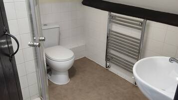A small bathroom with a toilet, a sink, and a shower.
