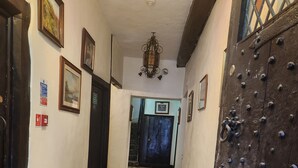A hallway with wooden flooring, a dark wooden door with metal studs, and several framed pictures on the walls. - Langley Inn (Bristol)