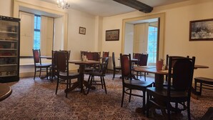 A dining area with wooden tables and chairs, a chandelier, and a patterned carpet. - Langley Inn (Bristol)