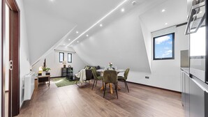 A modern kitchen with a dining area, wooden flooring, and a large window. - Spacious 1-bed Flat in Golders Green Near Station (London)