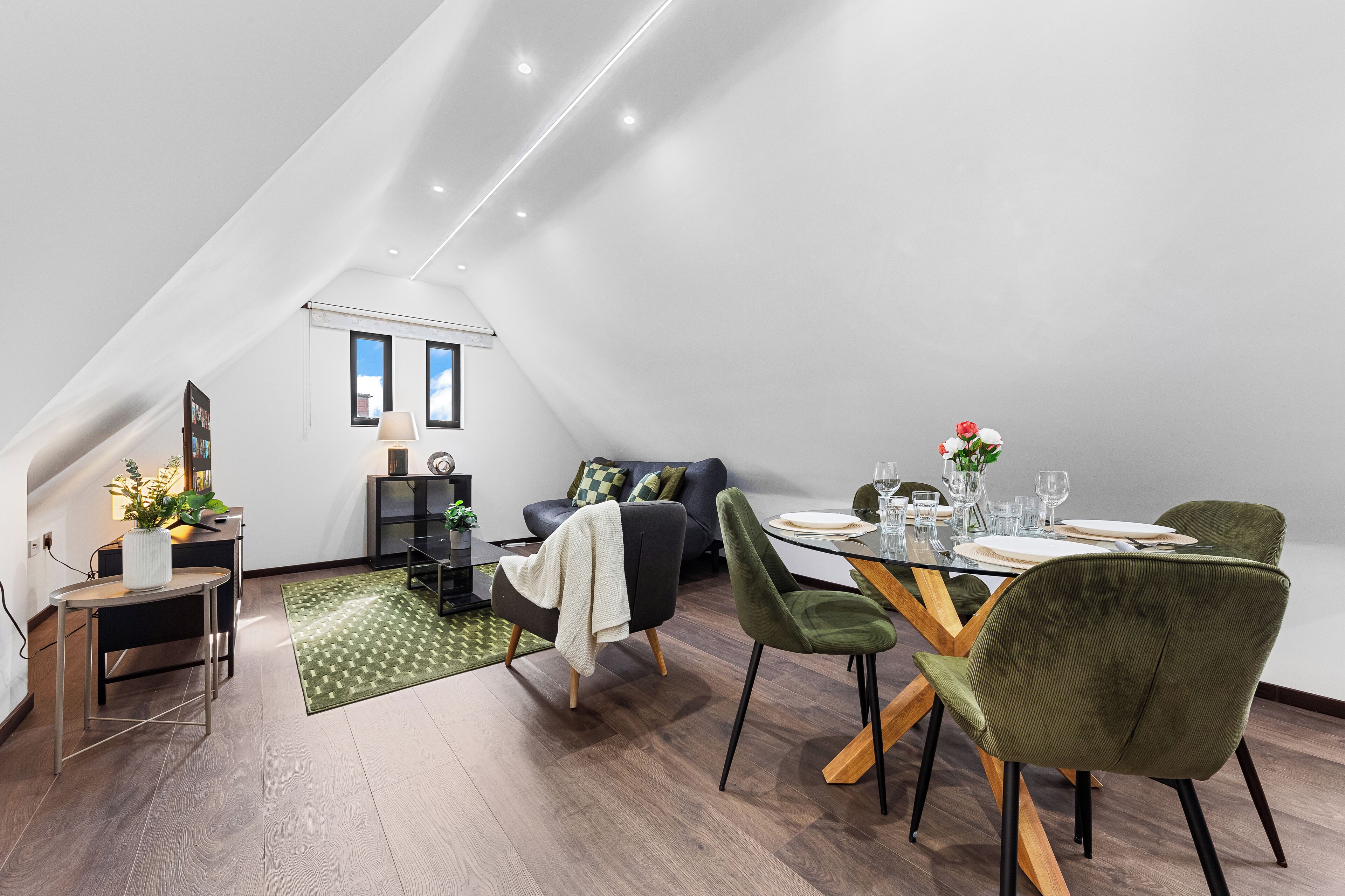 Een modern loft appartement met een eethoek, een bank en een trap naar een verdieping erboven.