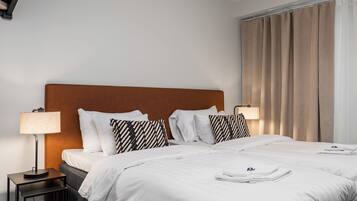 A hotel room with a large bed, two bedside tables, a lamp, and a window with curtains.