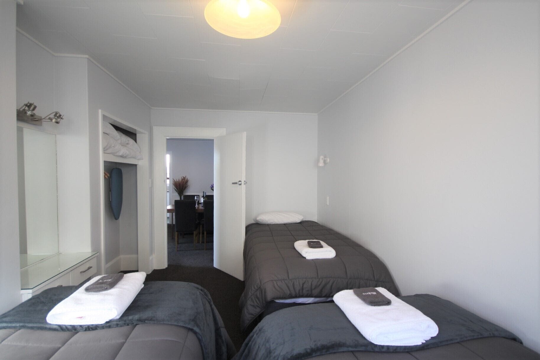 Ein Hotelzimmer mit zwei Einzelbetten, einer kleinen Sitzecke mit Tisch und Stühlen sowie einem Spiegel.