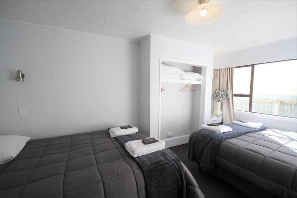 Een hotelkamer met twee bedden, een kledingkast en een groot raam.