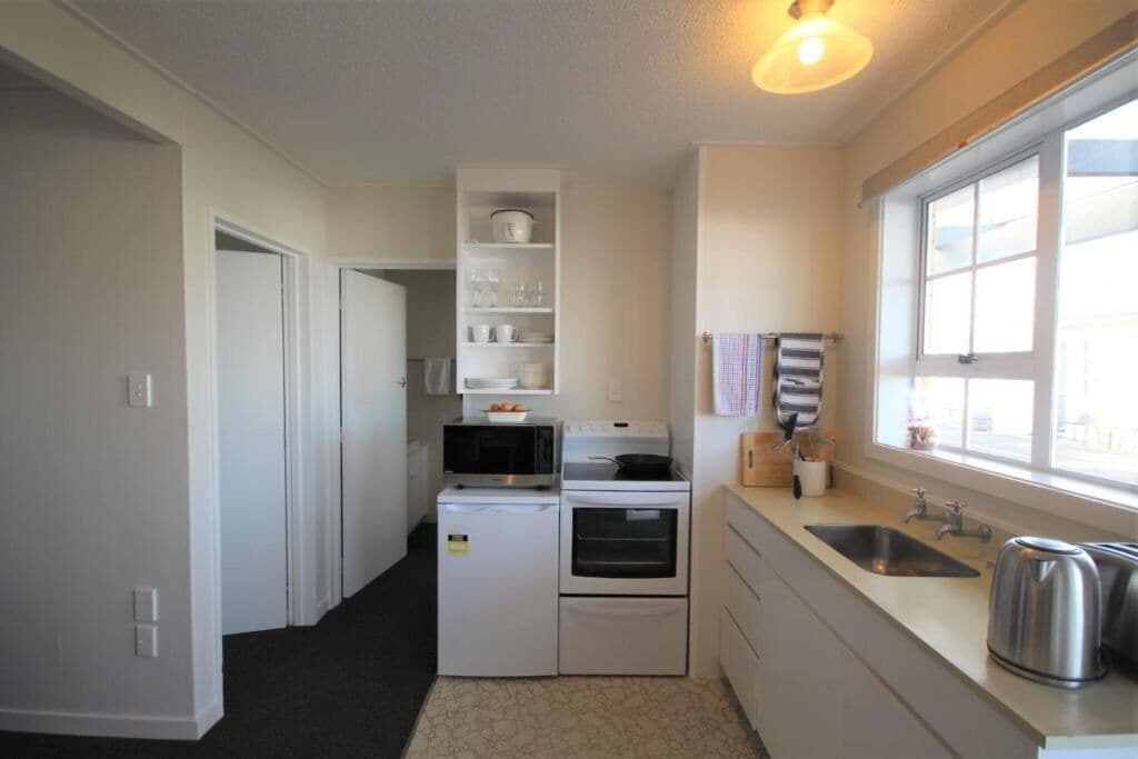 Eine kleine Küche mit Kühlschrank, Mikrowelle, Backofen und Spüle.