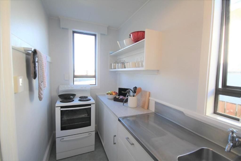 Una cocina compacta con estufa, horno y una ventana sobre el fregadero.