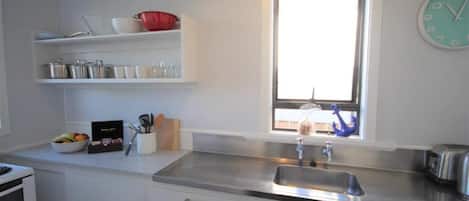 Cocina moderna con armarios blancos, un lavamanos de acero inoxidable y una ventana con vistas.