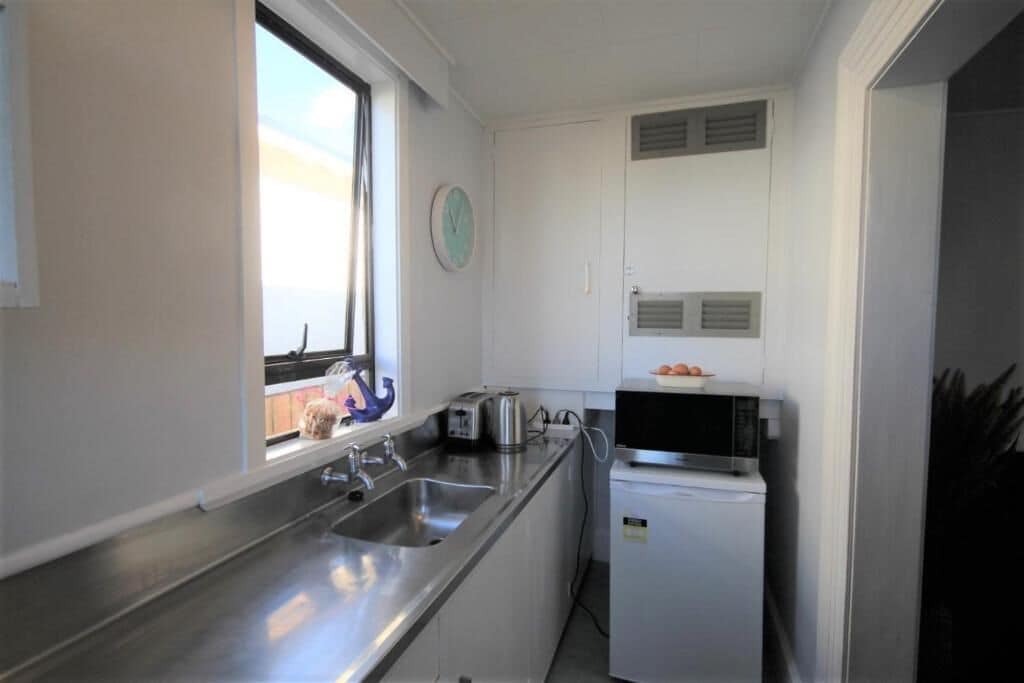 A compact kitchen with a window, stainless steel sink, toaster, and microwave.