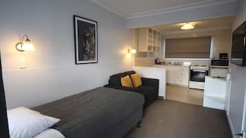 Ein gemütlicher Raum mit Bett, Sofa, Küchenzeile und einem Bild in einem Rahmen an der Wand.