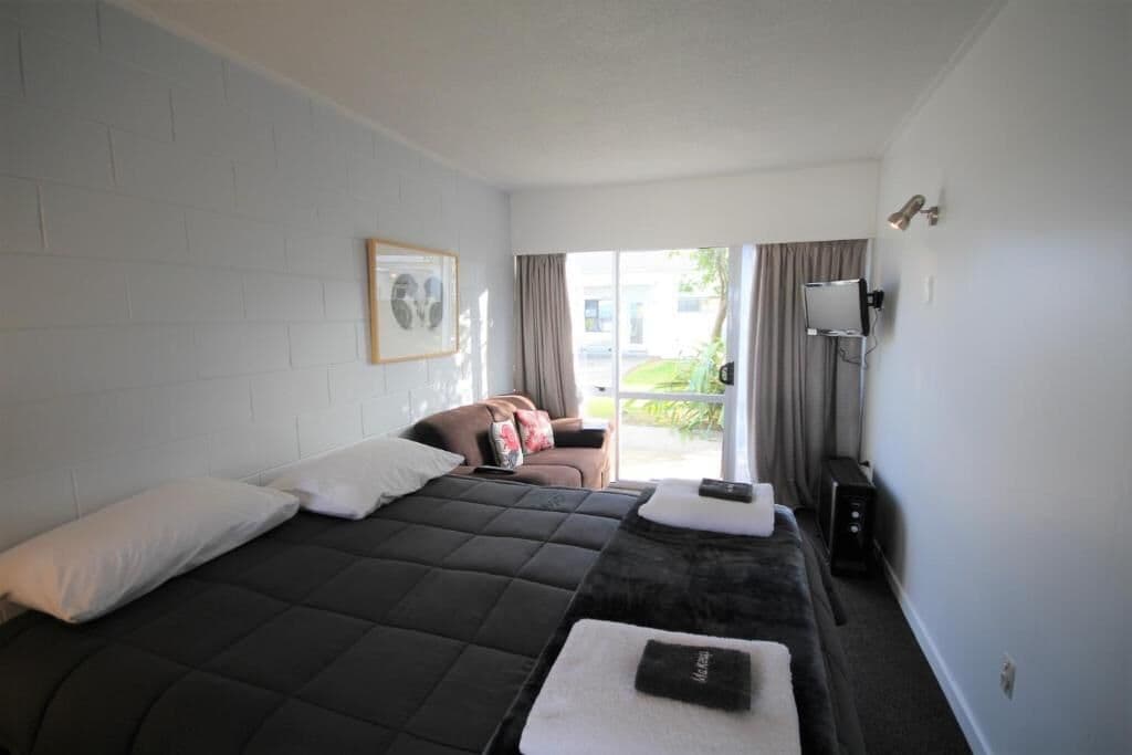 Une chambre d’hôtel avec un grand lit, un canapé, un bureau et une fenêtre avec des rideaux.