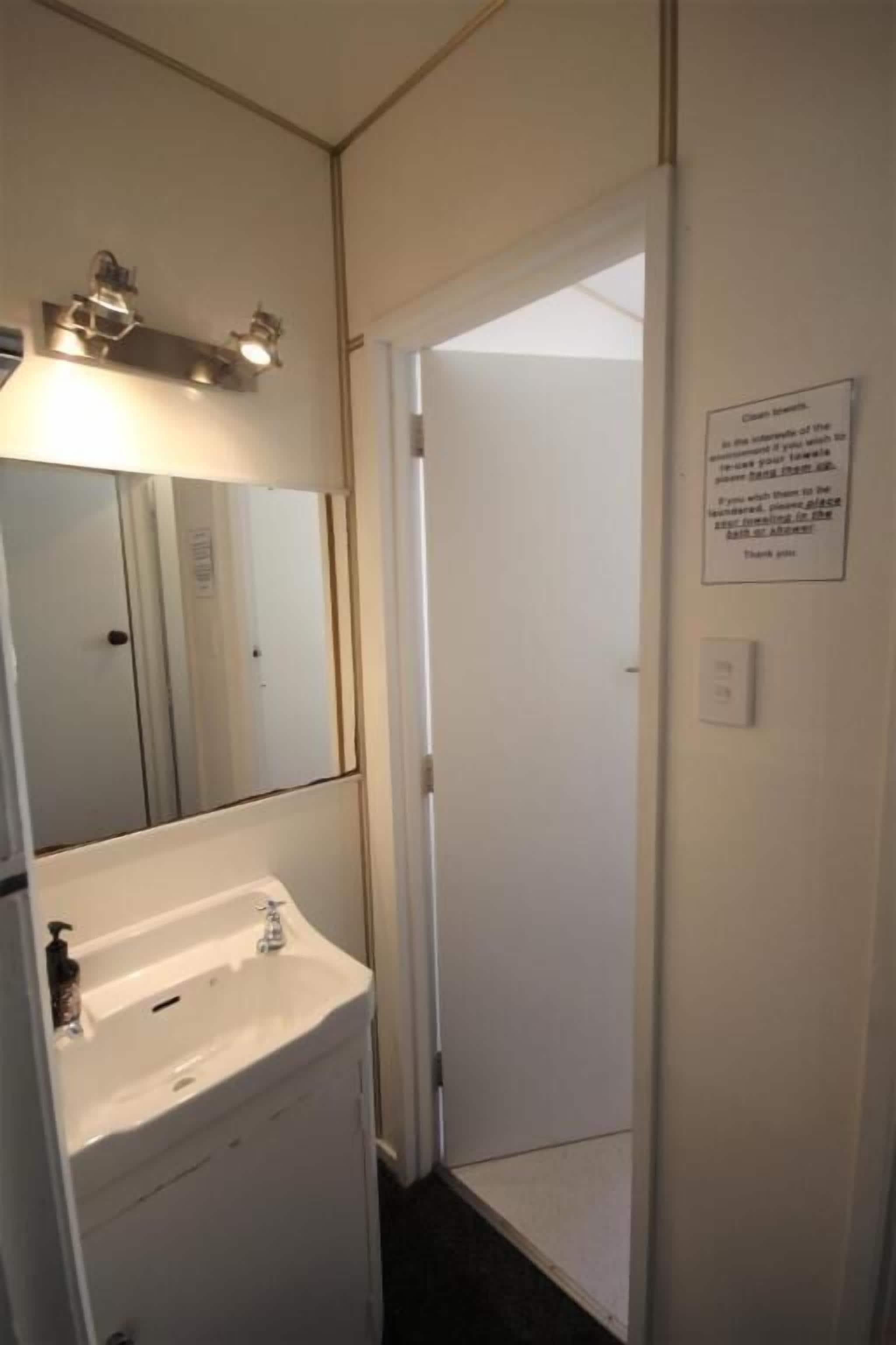 A bathroom with a sink, mirror, and a sign on the wall.