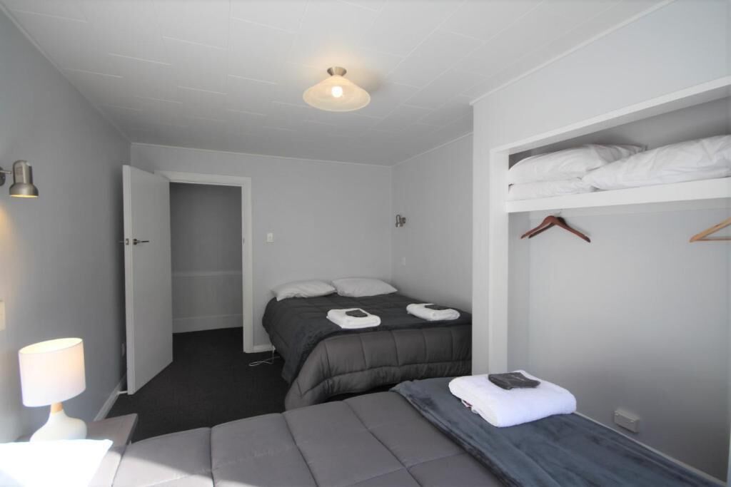 A bedroom with a bed, a bedside table with a lamp, a wardrobe, and a door leading to another room.