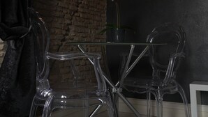 A dining area with a chandelier, clear chairs, a vase with white flowers, and a brick wall. - Rhome Luxury suite (Rome)