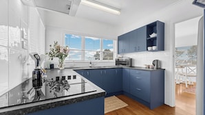 A modern kitchen with blue cabinets, a black countertop, and a window providing natural light.