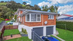 A two-story house with a garage, solar panels on the roof, and a well-maintained lawn.