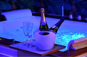 A room with a jacuzzi tub, two champagne flutes, and two bottles of champagne in a bucket. - DIMORA IL TARTUFO (Busso)