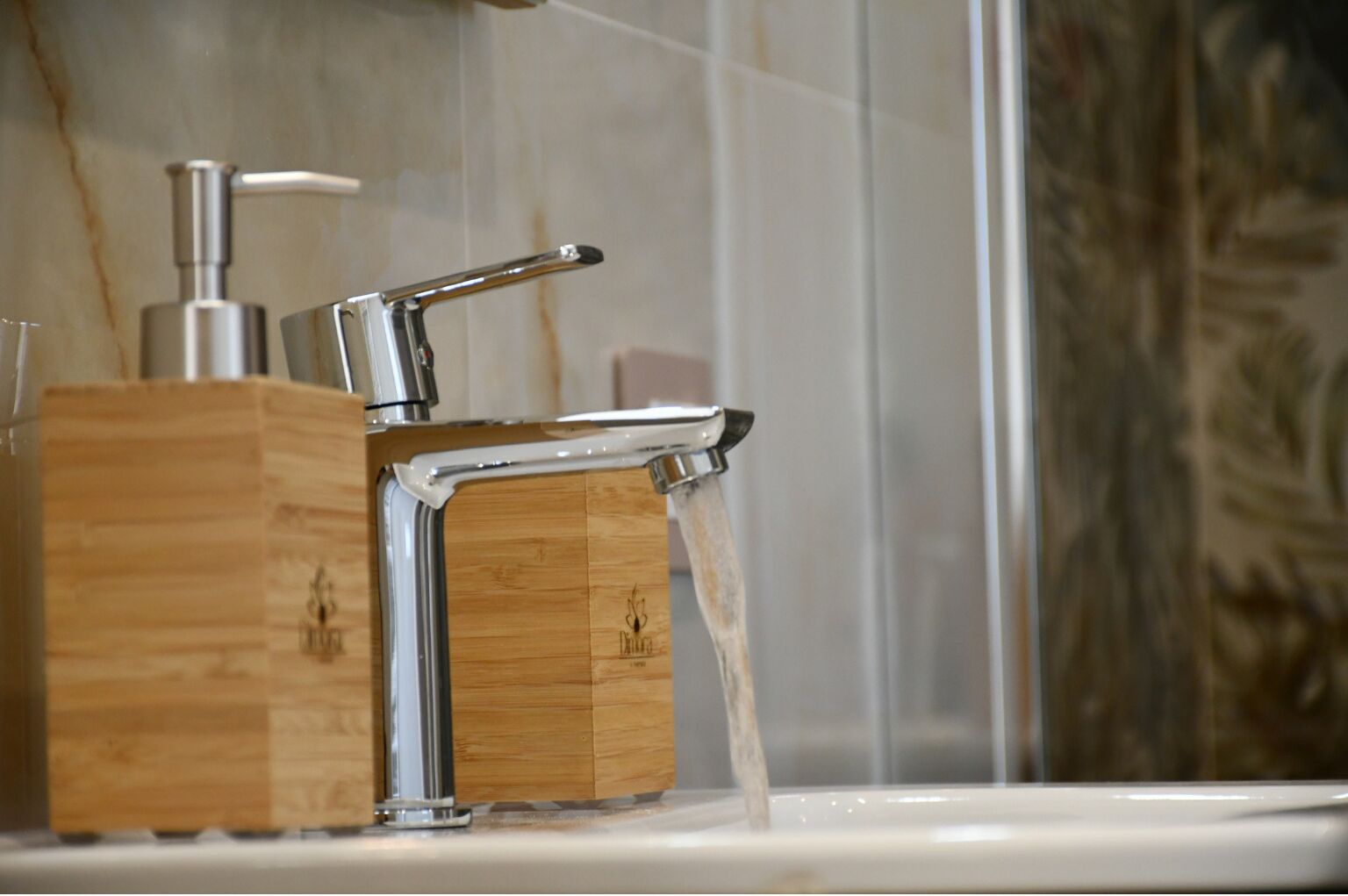 A modern bathroom with a chrome faucet and wooden soap dispenser.
