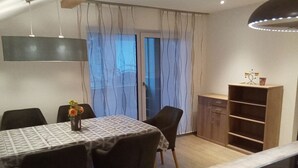 Een eethoek met een tafel, stoelen, een kast en een hanglamp.