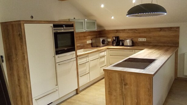Een moderne keuken met houten details, een inbouwoven, een magnetron en een koffiezetapparaat.