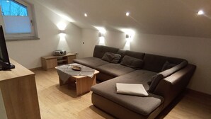 Een moderne woonkamer met een hoekbank, een salontafel en een klein houten bijzettafeltje.