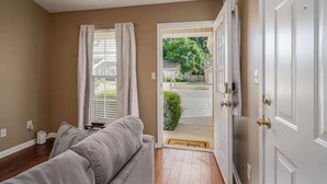 Una habitación con sofá, una puerta que da al exterior y una ventana con cortinas.