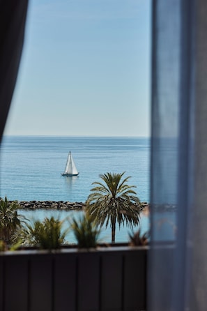 Un velero en aguas tranquilas, palmeras y una costa rocosa.