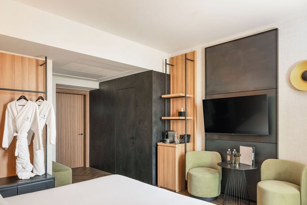 Une chambre d’hôtel moderne équipée d’un lit, d’une télévision, d’un coin salon et d’une armoire.