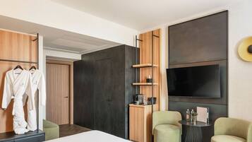 Une chambre d’hôtel moderne équipée d’un lit, d’une télévision, d’un coin salon et d’une armoire.