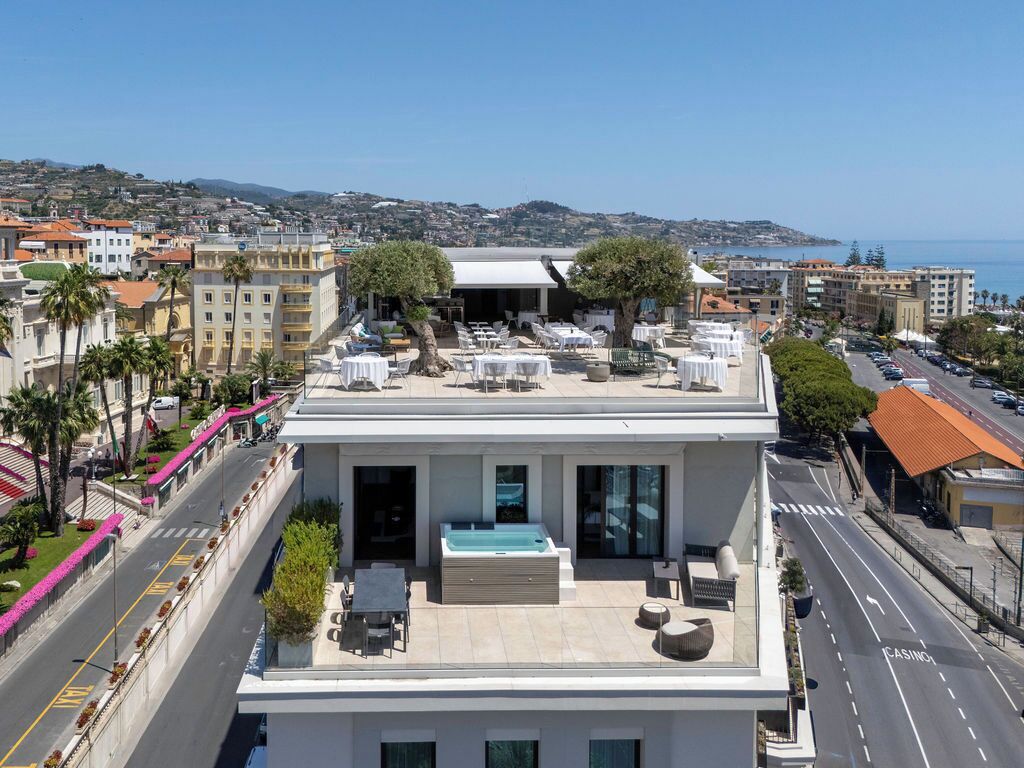 Terraza en la azotea con mobiliario exterior y bañera de hidromasaje, con vistas a una ciudad costera.
